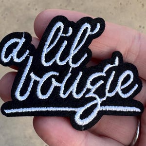 May include: Black iron-on patch with white embroidery that reads "a lil bougie".