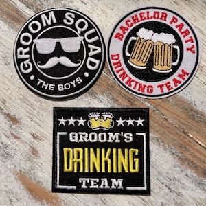 May include: Three embroidered patches for a wedding or bachelor party. One patch is black with white text that says "Groom Squad The Boys". Another patch is white with red and black text that says "Bachelor Party Drinking Team". The third patch is black with white text that says "Groom's Drinking Team".