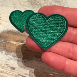 May include: Two green felt heart-shaped patches. The patches are about 2 inches in diameter.