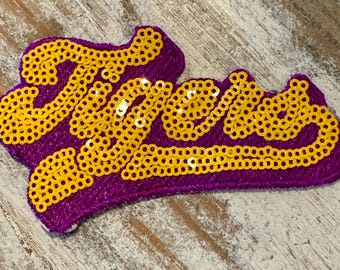 May include: Purple fabric patch with the word "Tigers" spelled out in gold sequins.