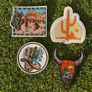 May include: Four embroidered iron-on patches with a western theme. The patches feature a cactus, a bull skull, a desert scene, and a cactus with a sunset.