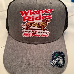 May include: Gray and black trucker hat with a Wiener Rides logo featuring a dachshund wearing a saddle. The logo also says "Only 25 Cents Free Today Only!" and has a BK Caps logo on the side.