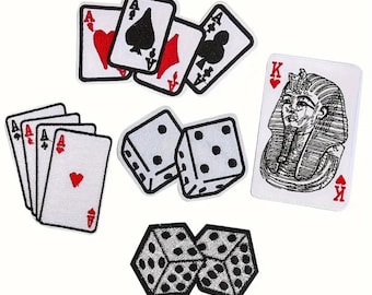 May include: A collection of embroidered patches featuring playing cards and dice. The set includes various aces, a king of hearts with an Egyptian pharaoh illustration, and two pairs of dice with black dots on white backgrounds, all with black borders.
