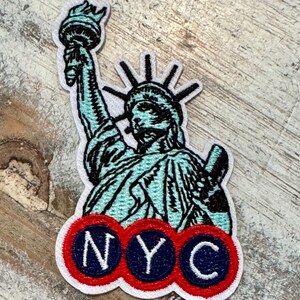 Pu&ograve; includere: Una toppa ricamata bianca con la Statua della Libert&eacute; con un contorno blu e nero e un logo NYC rosso, bianco e blu.