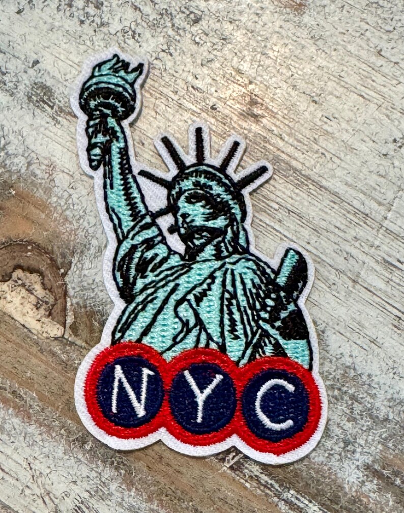 Pu&ograve; includere: Una toppa ricamata bianca con la Statua della Libert&eacute; con un contorno blu e nero e un logo NYC rosso, bianco e blu.