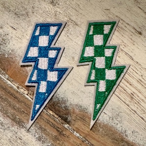 May include: Two iron-on patches in the shape of a lightning bolt. One patch is blue and white checkered, the other is green and white checkered.