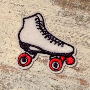 May include: A white roller skate patch with black laces and trim, and red wheels. The patch is embroidered with a detailed design, perfect for adding to clothing or accessories. The roller skate is a classic design.
