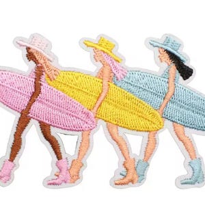 May include: Embroidered patch featuring three figures in hats and boots, each carrying a surfboard. The figures are in pink, yellow, and blue, with matching surfboards. The patch has a white border.