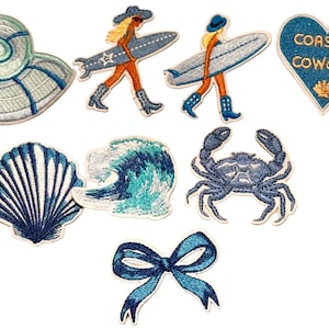 May include: A collection of eight embroidered patches featuring a spiral seashell, two figures carrying surfboards, a heart-shaped patch with the text COASTAL COWGIRL, a scallop shell, a crashing ocean wave, a blue crab, and a blue ribbon bow.