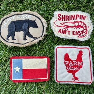 May include: Four embroidered patches with fringed edges. One features a bear and the text "DON'T POKE". Another says "SHRIMPING AIN'T EASY" with a shrimp graphic. A Texas flag patch and a "FARM FRESH" chicken patch are also shown.