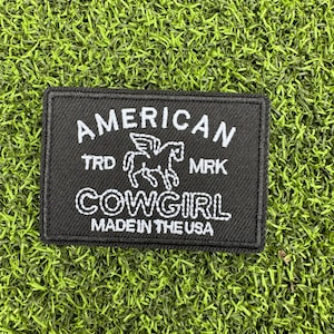 May include: Black embroidered patch with white text that reads "AMERICAN TRD MRK COWGIRL MADE IN THE USA" and a white silhouette of a horse with wings.