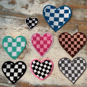 May include: Set of eight checkered heart patches in various colors, including black, white, pink, blue, and green. The patches are all heart-shaped and have a checkered pattern.