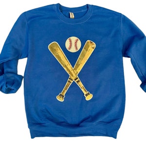 May include: A royal blue sweatshirt with a gold sequined baseball bat and ball design.
