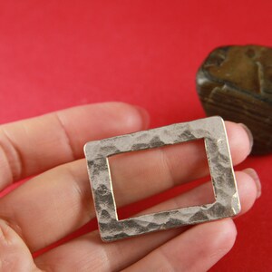 May include: A silver-toned metal frame with a hammered texture. The frame is rectangular with a square opening in the center.
