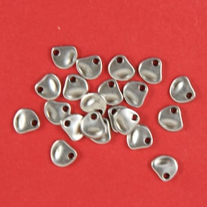 May include: A pile of silver metal charms shaped like a teardrop with a small hole at the top.