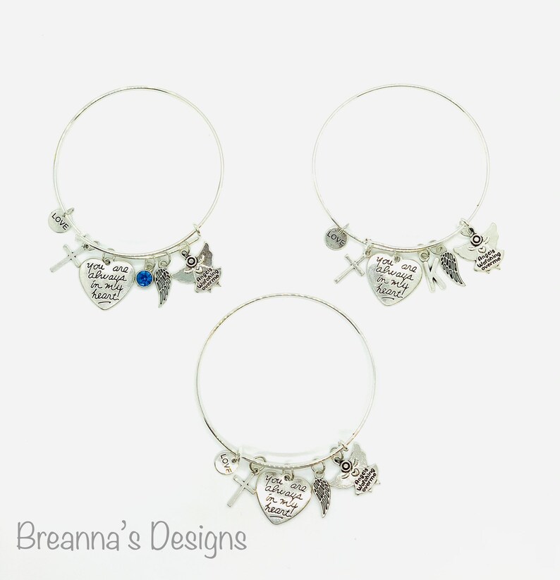 Peut inclure: Trois bracelets en argent avec des breloques. Chaque bracelet est orn&eacute; d'un pendentif en forme de c&oelig;ur avec le texte "You are always in my heart!" Les breloques comprennent une croix, un strass bleu, une aile d'ange et un petit pendentif ange.