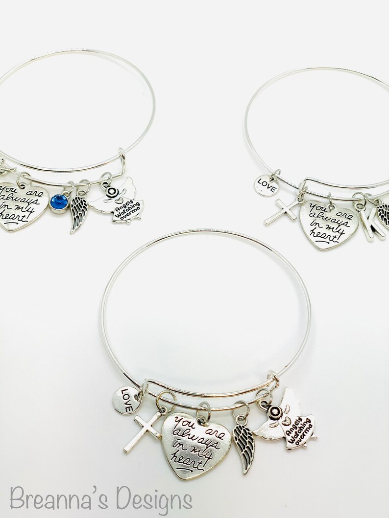 Peut inclure: Trois bracelets en argent avec des breloques, dont un c&oelig;ur avec le texte "you are always in my heart", une croix, une aile et un petit charme rond avec le mot "LOVE".