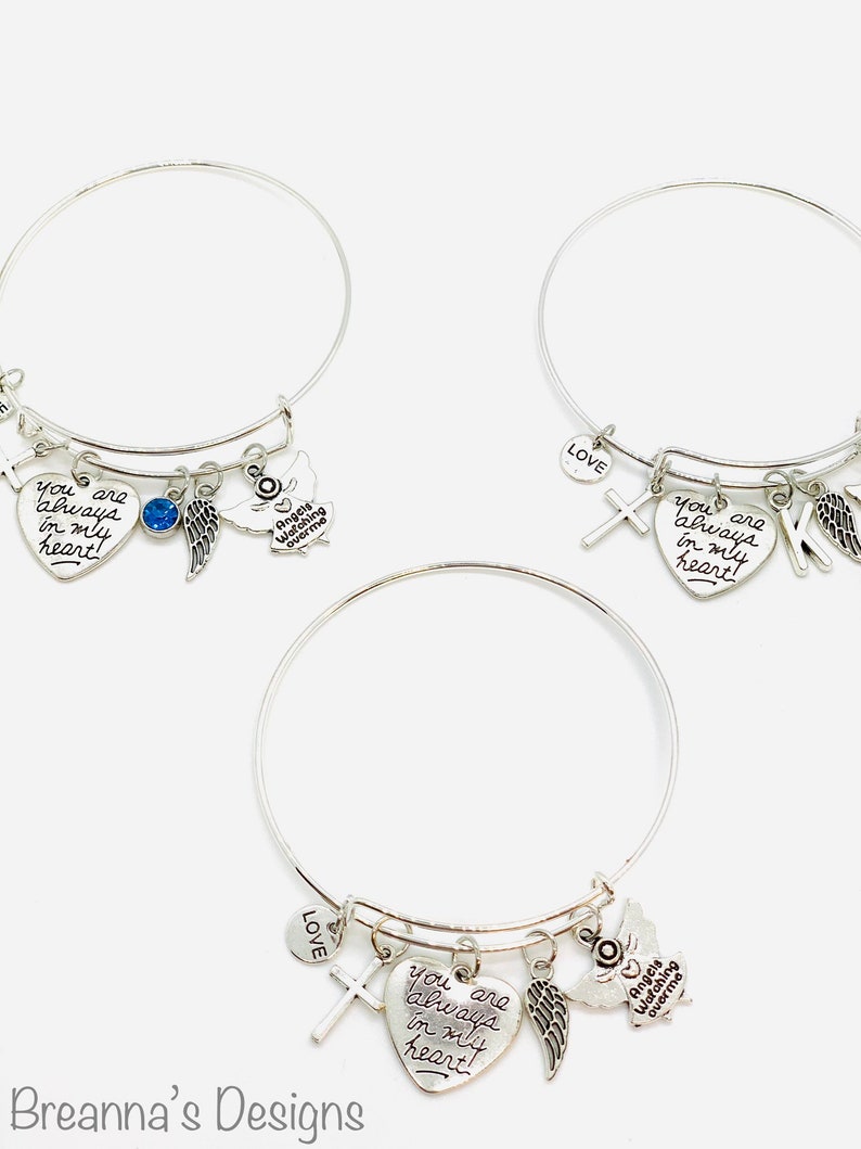 Peut inclure: Trois bracelets en argent avec un charme en forme de c&oelig;ur qui dit "You are always in my heart!" Chaque bracelet a un charme en forme de croix, un charme en forme d'aile d'ange et un charme en forme d'ange qui dit "Angels Watching Over Me".