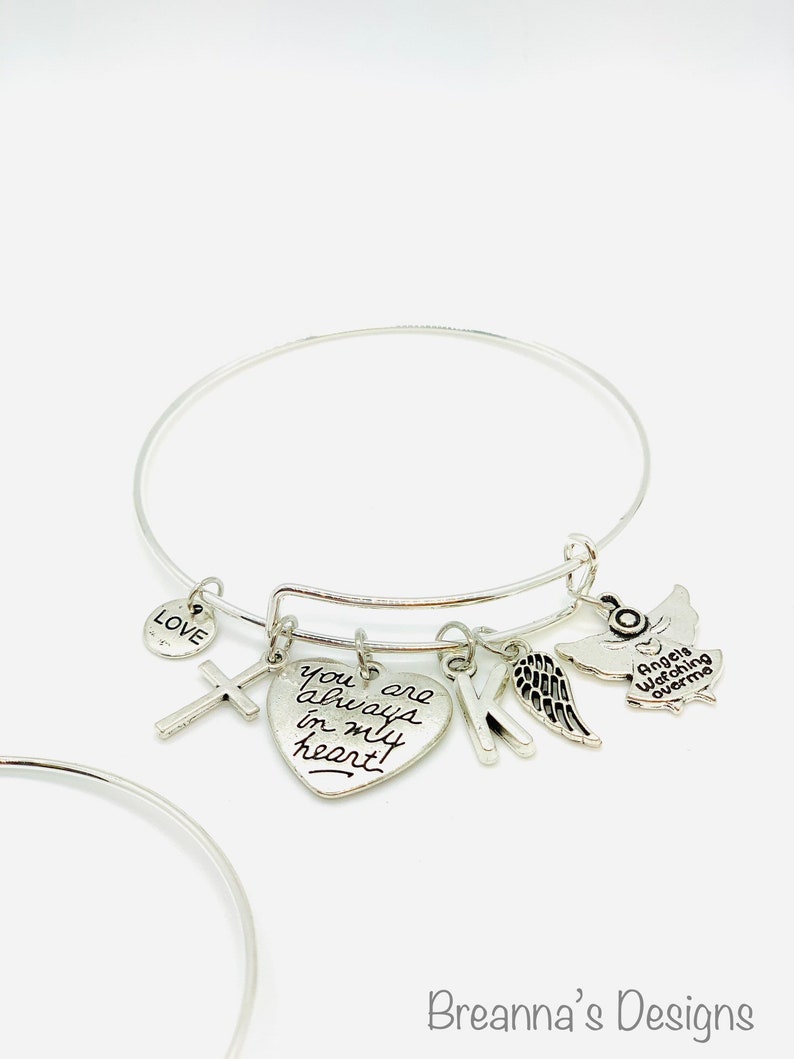 Peut inclure: Bracelet en argent avec un charme en forme de c&oelig;ur qui dit "You are always in my heart", un charme en forme de croix, un charme en forme de lettre K, un charme en forme d'aile d'ange et un charme en forme d'ange qui dit "Angels watching over me".