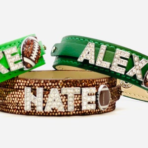 May include: Three leather bracelets with rhinestones spelling out the names "Duke", "Alex", and "Nate". Each bracelet features a brown football charm.