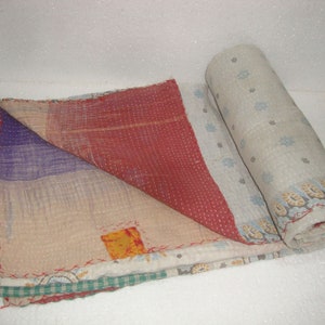 May include: A hand-stitched kantha quilt with a patchwork design featuring shades of red, purple, and beige. The quilt is made of recycled saris and has a unique, vintage look.
