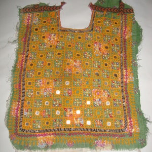 May include: A green fabric panel with a yellow and orange embroidered design. The design features small squares with mirrored accents and floral patterns.