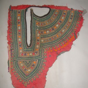 May include: A red fabric neckline with intricate embroidery in shades of green, blue, orange, and white. The embroidery features geometric patterns and beads.