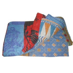 May include: A colorful patchwork quilt made from recycled saris. The quilt is blue, red, orange, and white with a variety of patterns. It is folded in half and the edges are visible.