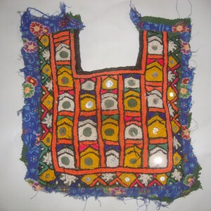 May include: A colorful embroidered fabric panel with a geometric pattern and small mirrors. The panel is trimmed with a blue and green fabric border.