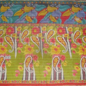 May include: A colorful textile with a repeating pattern of paisley and floral designs. The top section features stylized bird and leaf motifs in shades of blue, yellow, and green. The central section showcases large paisley shapes with red and yellow flowers.