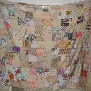 Puede incluir: Una colcha de retazos hecha con varias telas en tonos beige, marrón y blanco. La colcha está compuesta por muchos cuadrados y rectángulos diferentes, cada uno con un patrón único. La colcha es un hermoso ejemplo de artesanía hecha a mano.