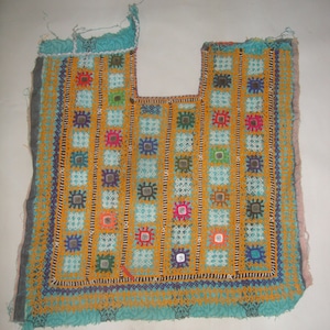 May include: A turquoise fabric panel with a decorative embroidered design. The embroidery features a repeating pattern of small squares with colorful thread and tiny mirrors.