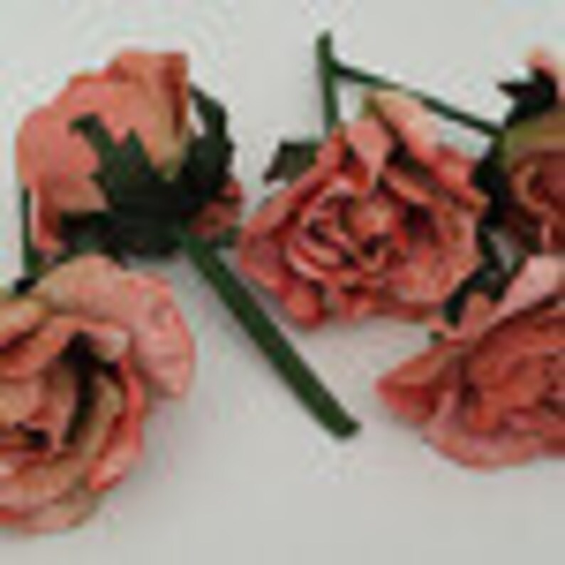 May include: Five pink fabric roses with green stems. The roses are arranged in a cluster, with the stems pointing in different directions.