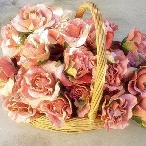 May include: A wicker basket overflowing with a large arrangement of blush pink silk roses.