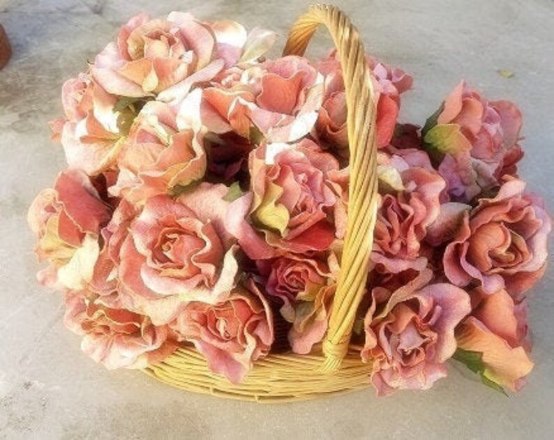 May include: A wicker basket overflowing with a large arrangement of blush pink silk roses.