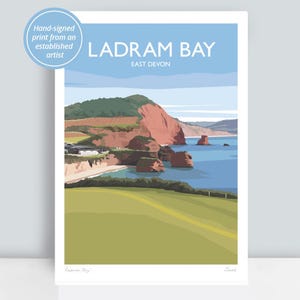 May include: A print of Ladram Bay, East Devon, depicting a coastal landscape with red cliffs, green fields, and the sea. The artwork includes the text "LADRAM BAY" and "EAST DEVON". A badge reads "Hand-signed print from an established artist."