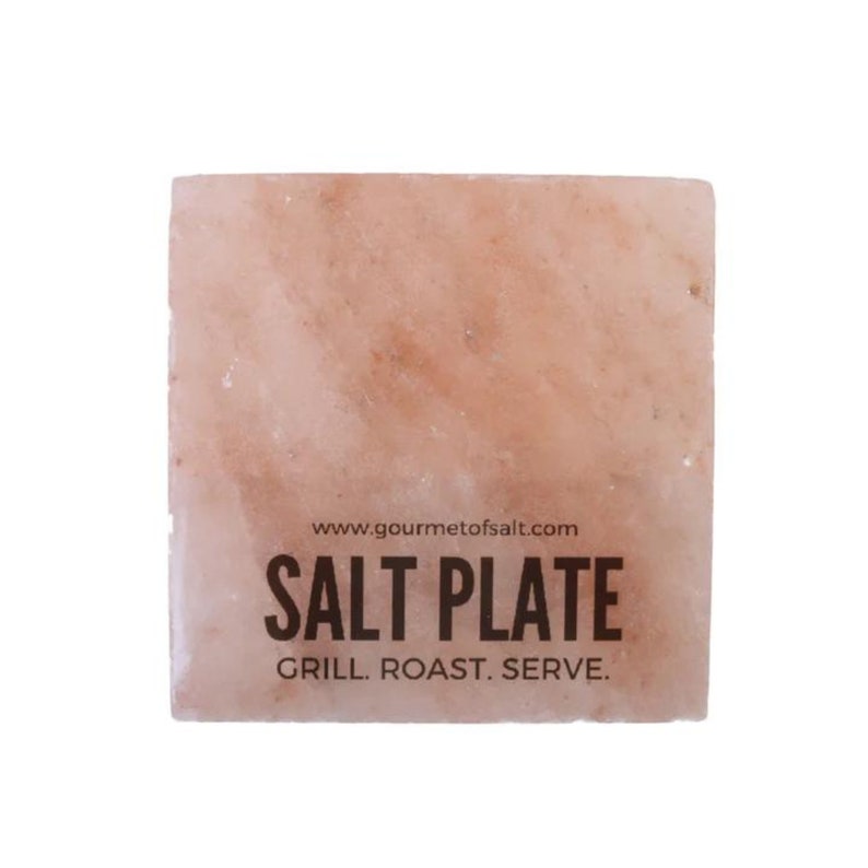 Op de afbeelding: Een vierkante roze Himalaya-zoutplaat met de tekst "www.gourmetof salt.com SALT PLATE GRILL. ROAST. SERVE."