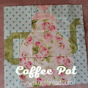 May include: A patchwork quilt block featuring a coffee pot design. The coffee pot is made of pink and green fabric with a floral print. The block is surrounded by a blue fabric with white hearts.