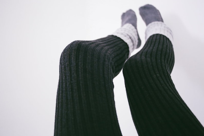 A close-up image of a woman wearing black ribbed leggings.