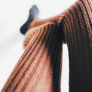 A close-up image of a woman's legs while wearing brown ribbed knitted leggings.