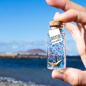 Avventura vi aspetta. Mare. Barchetta di carta. Messaggio in una bottiglia. Miniature. Regalo personalizzato. Divertente cartolina d'amore.