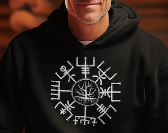 May include: A black hooded sweatshirt with a white design of a compass with a tree in the center. The sweatshirt is worn by a person sitting on a stack of wooden logs.