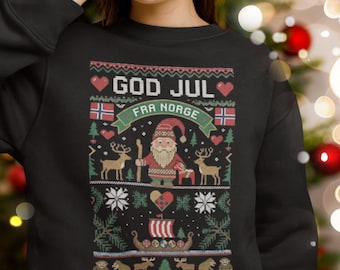May include: A black sweatshirt featuring a graphic print with the text GOD JUL FRA NORGE, a Santa Claus figure, reindeer, a Viking ship, and Norwegian flags, worn with a red and white Santa hat.