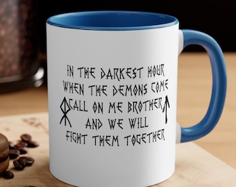 Könnte beinhalten: Weiße Keramiktasse mit blauem Rand und Henkel. Die Tasse zeigt eine schwarz-weiße Grafik mit dem Text "IN THE DARKEST HOUR WHEN THE DEMONS COME CALL ON ME BROTHER AND WE WILL FIGHT THEM TOGETHER".