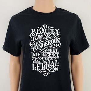 May include: Black t-shirt with a white graphic print that reads "Beauty may be dangerous but intelligence is lethal" with a skull graphic.