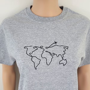 K&ouml;nnte beinhalten: Ein hellgraues T-Shirt mit einer einfachen Linienzeichnung der Welt und einem kleinen Flugzeug dar&uuml;ber.
