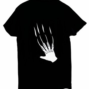 May include: Black t-shirt featuring a white graphic of a hand with long, sharp claws. The clawed hand design is centered on the shirt. The t-shirt is made of a soft material.