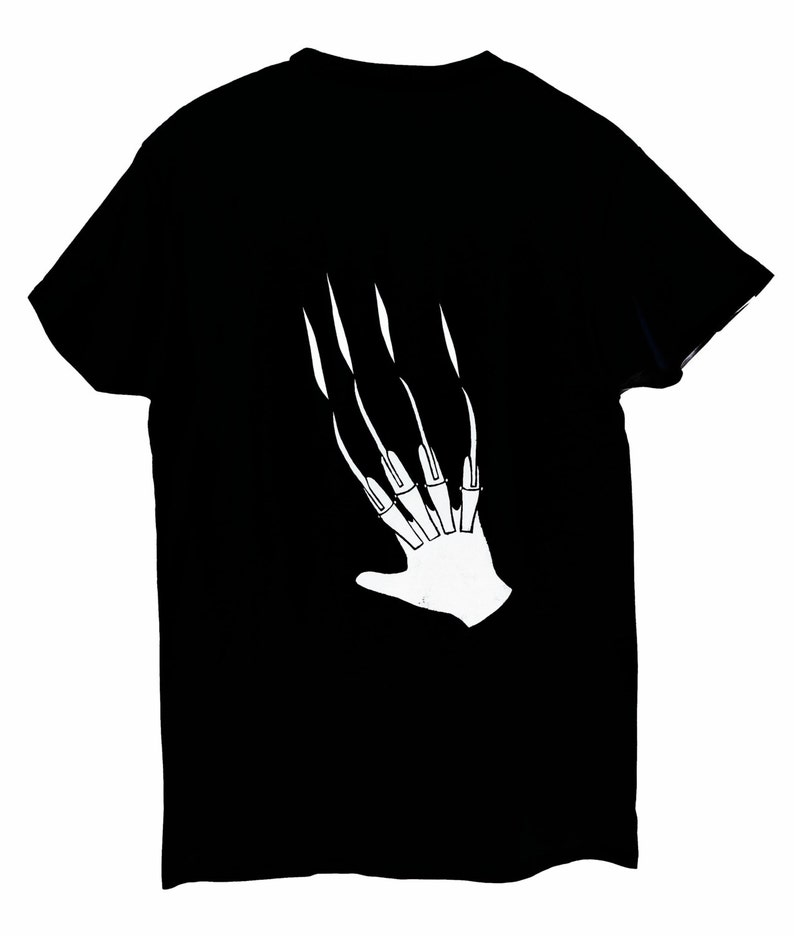 May include: Black t-shirt featuring a white graphic of a hand with long, sharp claws. The clawed hand design is centered on the shirt. The t-shirt is made of a soft material.