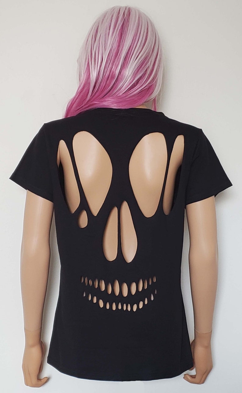 May include: Black t-shirt with a skull cut-out design on the back. The skull is made of holes in the fabric, revealing the skin underneath.
