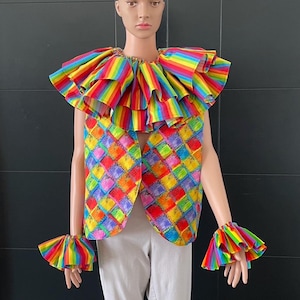 Könnte beinhalten: Ein farbenfrohes Clownskostüm mit einer regenbogen gestreiften Weste, einem Rüschenkragen und passenden Armbinden. Die Weste hat ein kariertes Muster mit Quadraten in verschiedenen Farben.